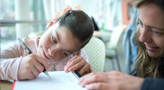 Gillette patient Maria renata writing with her mom, school services