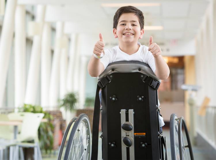 Gillette patient on stander giving two thumbs up in skyway