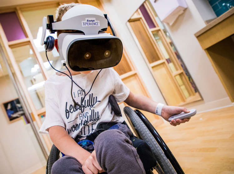 Patient in a wheelchair uses a VR headset donated through our partnership with the Starlight Foundation