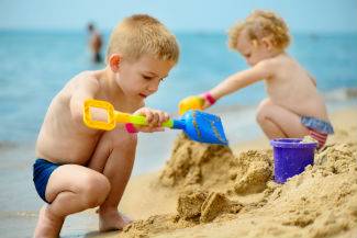Two little kids playing in sand on the beach