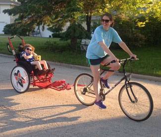 Kira, who has Rett syndrome, enjoys biking with her family.
